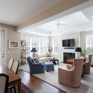 A cozy and elegantly furnished living room with a fireplace and ample natural light.
