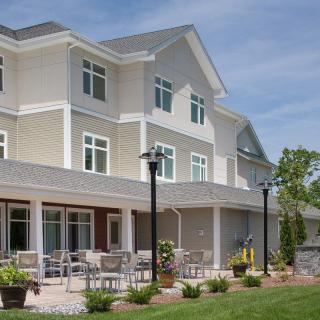 A modern residential building with outdoor seating and landscaped grounds.