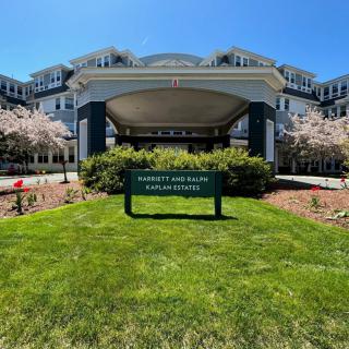 A hotel entrance surrounded by well-maintained lawns and blooming trees.