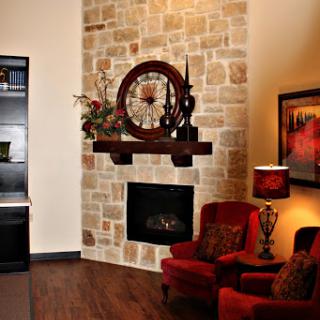A cozy living room featuring a stylish stone fireplace and comfortable red chairs.