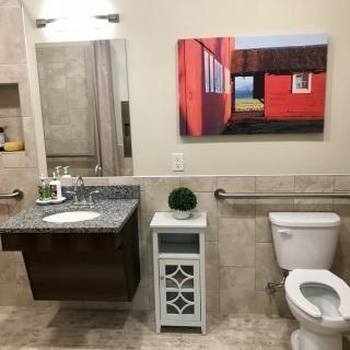 A modern bathroom featuring a wall-mounted sink, toilet, and decorative painting.