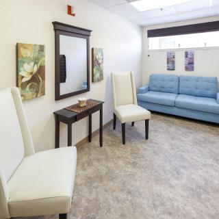 A modern waiting room with white chairs, a blue sofa, and decorative artwork.