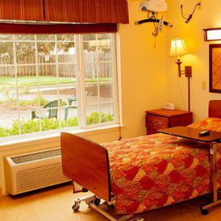 A cozy hospital room with a large window, providing a view of the garden outside.