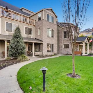 A well-maintained residential building with a manicured lawn and surrounding trees.