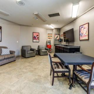 A cozy lounge room featuring a large TV, comfortable seating, and wall artwork.