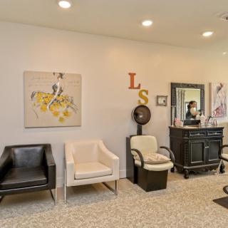 A modern salon interior featuring stylish chairs, wall art, and a large mirror.