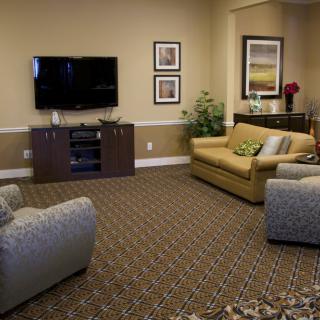 A cozy living room with a television, sofa, armchairs, and decorative elements.