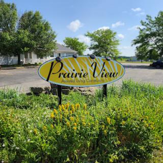 A welcoming sign for Prairie View surrounded by lush greenery and a clear blue sky.