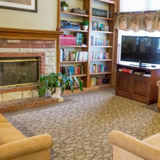 A cozy living room with a fireplace, bookshelves, and a television.