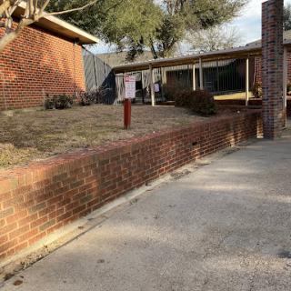A view of a residential building with a brick wall and a driveway.