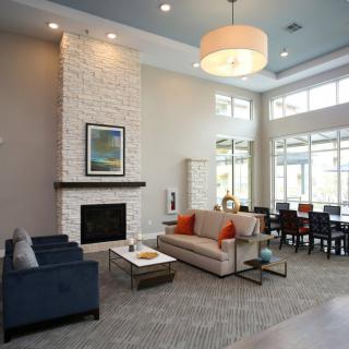 A modern living room with a fireplace, comfortable seating, and natural light from large windows.