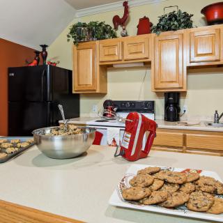 A kitchen scene featuring freshly baked cookies on a countertop, with a mixer and baking ingredients in the background.