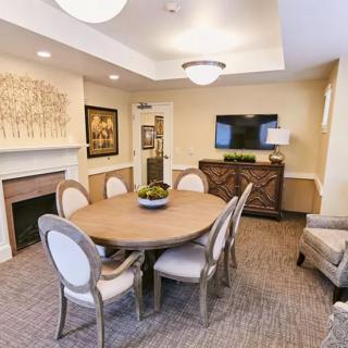 A cozy dining room featuring elegant furniture, a round table, and a warm fireplace.