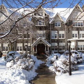 A snow-covered building with a tree-lined pathway.