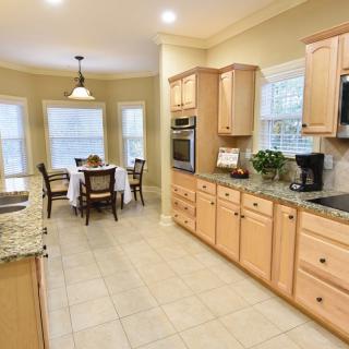 A bright and modern kitchen with wood cabinets, granite countertops, and a cozy dining area.