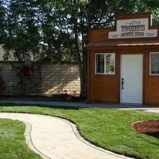 A small wooden building with a pathway in a grassy yard.