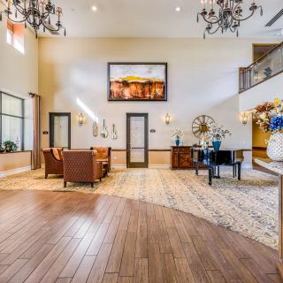 A spacious and elegantly decorated lobby featuring comfortable seating, chandeliers, and wood flooring.