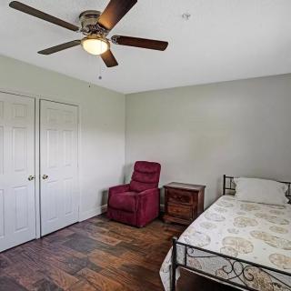 A simple bedroom with a bed, red armchair, and wooden flooring.