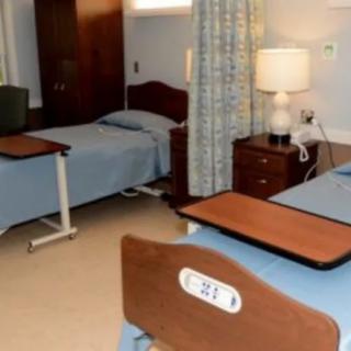 A hospital room with two beds and standard medical furniture.