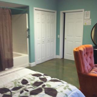 A cozy bedroom with a view of the bathroom, featuring a comfy chair and closet.