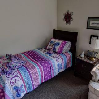 A cozy bedroom with a vibrant, patterned single bed and a neatly arranged nightstand.
