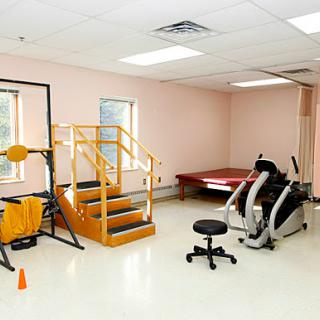 A well-equipped rehabilitation gym featuring various exercise machines and a set of stairs for physical therapy.