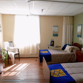 A bright and inviting bedroom with two beds, decorated in calming colors and illuminated by natural light.