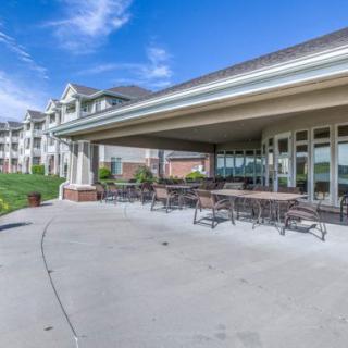 A spacious outdoor patio area with tables and chairs, adjacent to a building under a clear blue sky.