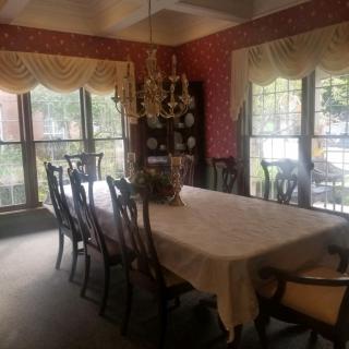 A formal dining room with a large table, ornate chandelier, and elegant decor.
