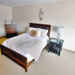 A cozy and modern bedroom featuring a neatly made bed, bedside lamp, and stylish decor.