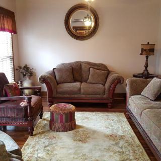 A cozy living room with sofas, an armchair, a mirror, and a lamp.