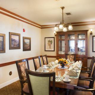 A well-decorated dining room with a large table set for a meal, surrounded by elegant chairs and adorned with wall art.