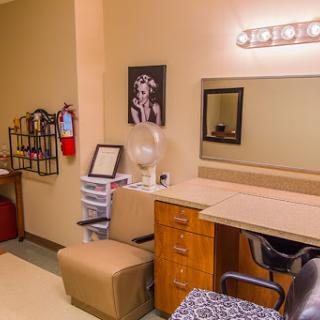 A well-organized beauty salon makeup station with a mirror and comfortable seating.