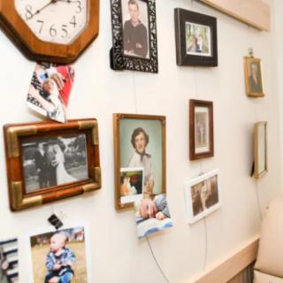 A wall adorned with various framed family photographs and a clock, showcasing personal memories in a cozy home setting.