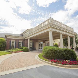 A beautifully designed entrance to a building featuring elegant columns and colorful landscaping.