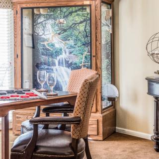 A cozy dining room setup with a wooden table and chairs, complemented by a large decorative cabinet and framed artwork in the background.
