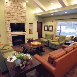 A cozy living room with a stone fireplace, comfortable seating, and a television.