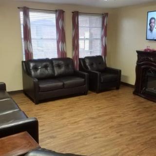 A cozy living room with multiple couches, a television, and windows providing natural light.