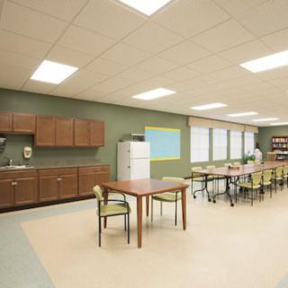 A modern classroom with tables, chairs, cabinets, and a whiteboard.