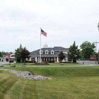 A building with a flagpole and landscaped lawn under a cloudy sky.