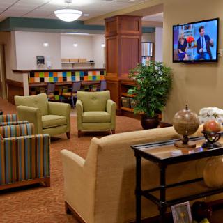 A cozy lobby seating area featuring comfortable chairs, a coffee table, and a television.