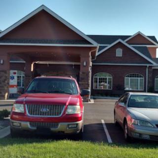 A parking lot in front of a brick building with two parked vehicles during the daytime.