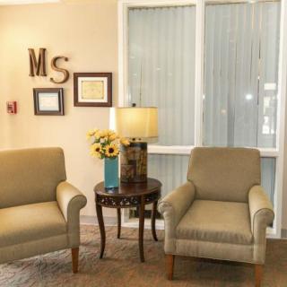 A cozy living room setup with two armchairs, a small round table with a lamp, and decorative elements on the wall.