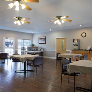 A spacious and inviting dining area featuring tables, chairs, and ceiling fans, designed for community gatherings.