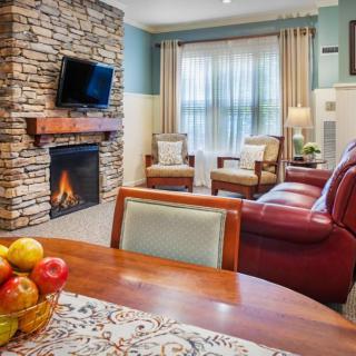 A cozy living room with a stone fireplace, television, and comfortable seating.