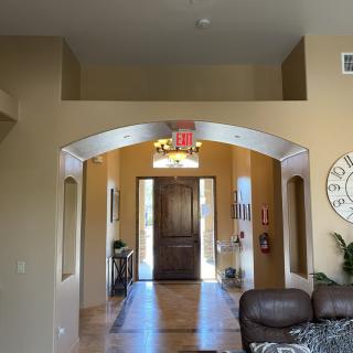 A welcoming home entrance with an archway leading to a wooden front door, surrounded by tasteful interior decor.