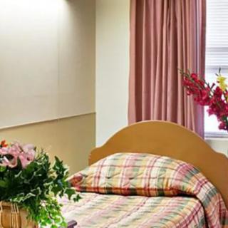 A cozy bedroom with a plaid bedspread and floral decorations.