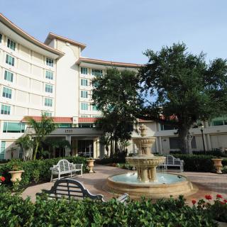 A scenic view of a hotel exterior with a fountain and garden area.