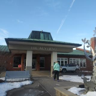 A winter view of a building with snow on the ground and a person approaching the entrance.