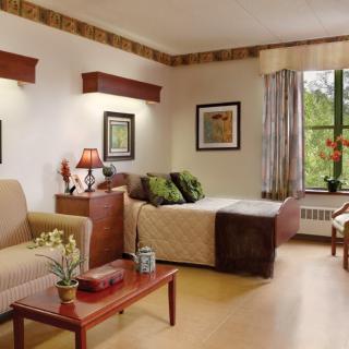 A cozy, well-decorated room with a bed, sofa, table, and window.